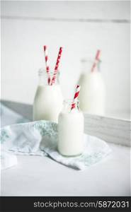Milk jar with red striped straws on white wooden background