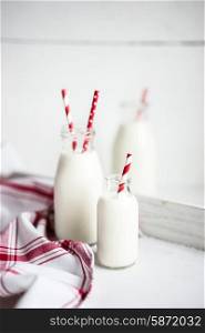 Milk jar with red striped straws on white wooden background