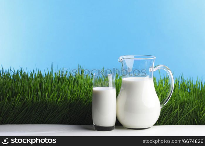 Milk jug and glass on grass field. Milk jug and glass on fresh green grass field background