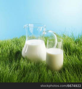 Milk jug and glass on grass field. Milk jug and glass on fresh green grass field background