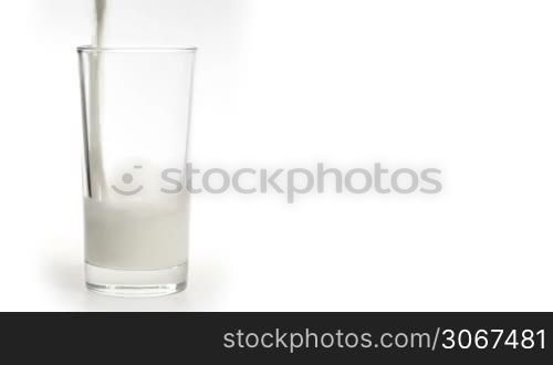 Milk pouring in the glass on a white background.
