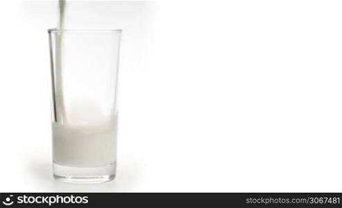 Milk pouring in the glass on a white background.