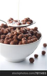 milk pouring into bowl with chocolate balls isolated