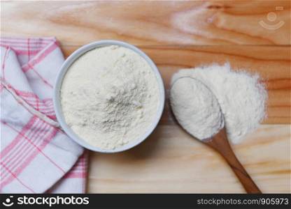 Milk powder in spoon and cup for baby on wooden table background