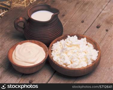 Milk, sour cream and curd on a wooden rustic board