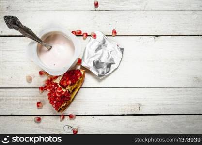Milk yoghurt with pomegranate. On a white wooden table.. Milk yoghurt with pomegranate.