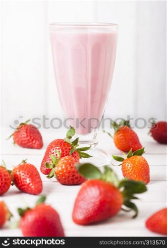 Milkshake glass with fresh summer berries smoothie on wooden background.Strwberry