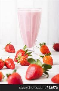Milkshake glass with fresh summer berries smoothie on wooden background.Strwberry