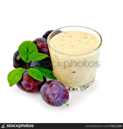 Milkshake in a glass with red plums and green leaves isolated on white background
