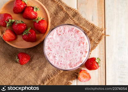 Milkshake with strawberries. Cold summer drink with berries on a wooden background.. Milkshake with strawberries. Cold summer drink with berries on wooden background.