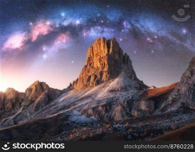 Milky Way acrh over beautifull rocks at starry night in summer in Dolomites, Italy. Landscape with purple sky with stars and bright arched milky way over high alpine rocky mountains. Space. Nature