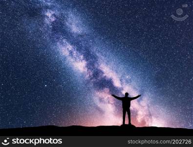 Milky Way and silhouette of a standing happy man with raised up arms. Travel in Nepal. Landscape with beautiful galaxy. Universe. Night sky with stars, colorful Milky Way. Starry sky and man. Space