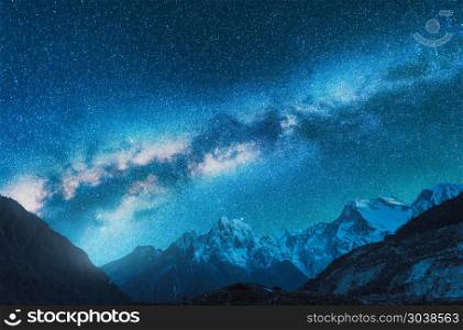 Milky Way and snowy mountains. Fantastic view with mountain ridge and starry sky at night in Nepal. Beautiful Himalayas. Night landscape with blue sky with stars and milky way. Galaxy.Space background. Milky Way and snowy mountains in Nepal at night