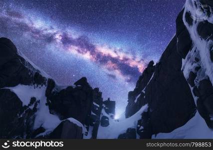 Milky Way and snowy mountains. Space. Beautiful nature. Snow covered rocks and starry sky at night. Mountain peak and purple sky with stars in Himalayas. Landscape with bright milky way. Galaxy. Milky Way and snowy mountains at starry night