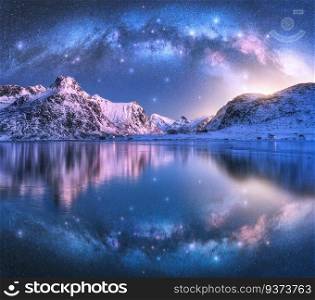 Milky Way arch above sea coast and snow covered mountains in winter at night. Lofoten Islands, Norway. Arctic landscape with starry sky, arched milky way reflected in water, snowy rocks. Space