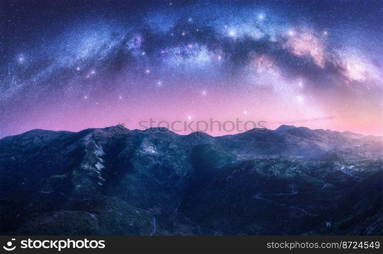 Milky Way arch over the mountains at starry night. Pink sky with bright stars and arched milky way in summer in Lefkada, Greece. Nature. Beautiful mountain landscape. Space background. Galaxy. Milky Way arch over the mountains at starry night