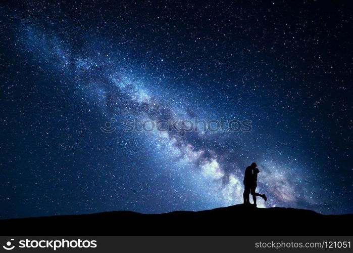 Milky Way. Night landscape with silhouettes of hugging and kissing man and woman on the mountain. Sky with stars. Silhouette of lovers. Couple, relationship. Blue milky way with people. Universe