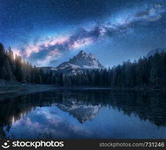 Milky Way over Antorno lake at night. Summer landscape with alpine mountains, trees, blue sky with milky way and stars, beautiful reflection in water, high rocks. Dolomites, Italy. Space and nature