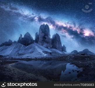 Milky Way over mountains at night in summer. Colorful landscape with alpine mountains, lake, blue sky with milky way and stars, reflection in water, high rocks. Dolomites, Italy. Space and galaxy