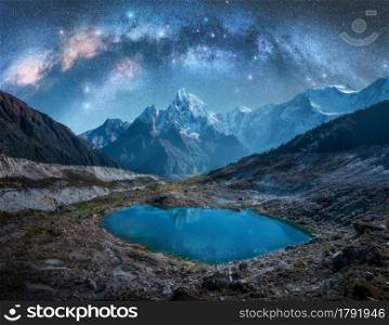 Milky Way over snowy mountains and lake at night. Landscape with snow covered high rocks, starry sky, reflection in water in Nepal. Sky with stars. Bright milky way in Himalayas. Space and nature