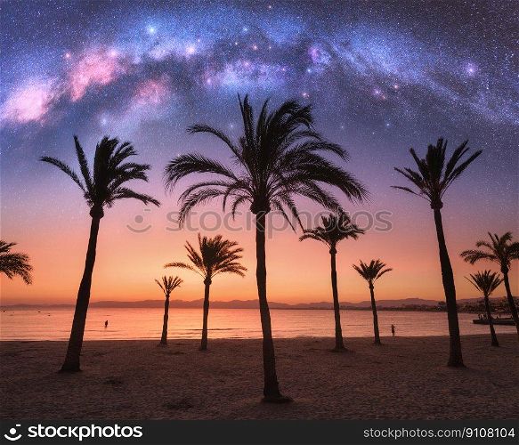 Milky Way over the sandy beach with palms at night in summer. Landscape with sea shore, beautiful starry sky, galaxy and silhouettes of palm trees at sunset. Travel in Mallorca, Spain. Space. Concept