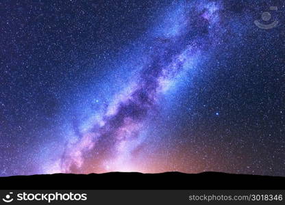 Milky Way. Space. Scenic night landscape with bright milky way, sky full of stars, orange light and hills. Shiny stars. Beautiful scene with universe. Space background with starry sky. Concept. Nature