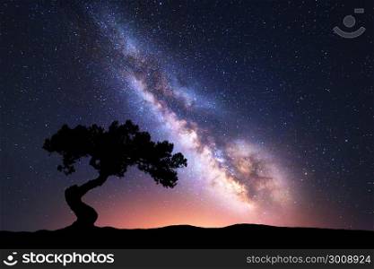 Milky Way with alone crooked tree on the hill. Colorful night landscape with bright milky way, starry sky and hills in summer. Space background. Amazing astrophotography. Beautiful universe. Travel
