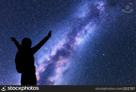 Milky Way with silhouette of a happy woman with backpack and raised up arms at night. Space background with sky with stars, bright colorful milky way, girl. Success. starry sky and woman. Night scene