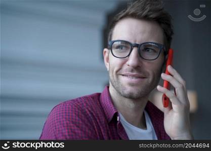 Millennial european man talking on smartphone while working distantly online from home,focused freelancer guy has urgent conversation with customer discussing new project and changes in business plans. Millennial european man talking on smartphone while working distantly online from home