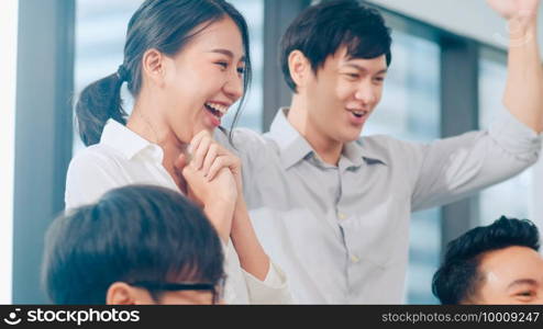 Millennial group of young businesspeople Asia businessman and businesswoman celebrate giving five after dealing feeling happy and signing contract or agreement at meeting room in small modern office.