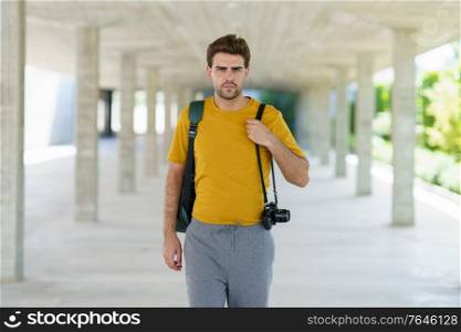 Millennial man traveling with a SLR camera outdoors. Millennial man taking photographs with a SLR camera