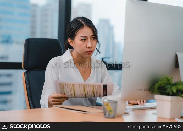 Millennial young Chinese businesswoman working stress out with project research problem on computer desktop in meeting room at small modern office. Asia people occupational burnout syndrome concept.