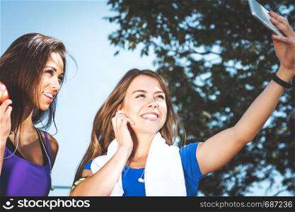 Millennials lifestyle concept - two sports girls take a selfie and smile while training outdoors on a sunny day ( vintage effect)