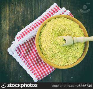 Millet cereal in a wooden plate on a red napkin, topr view