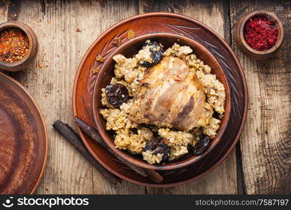 Millet porridge with chicken in bacon, with spices.Rustic food on a vintage wooden background.. Stewed chicken thighs and porridge