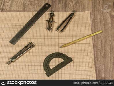 Millimeter paper and drawing accessories lie on a wooden surface