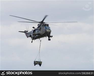 Miltary helicopter lifting a load in support of troops