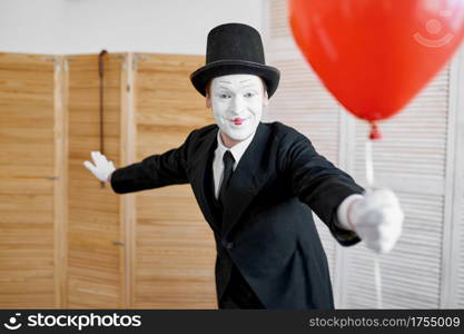 Mime artist with air balloon, comedy parody. Pantomime theater, comedian, positive emotion, humour performance, funny face mimic and grimace. Mime artist with air balloon, comedy parody