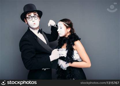 Mime artists with white makeup masks on faces. Pantomime theater actor and actress performing against black background. Comedy performers