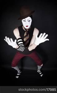 mime in hat, tie and white gloves on black background