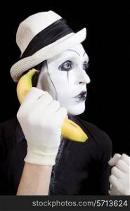 mime in white hat holding a banana in his hand close up
