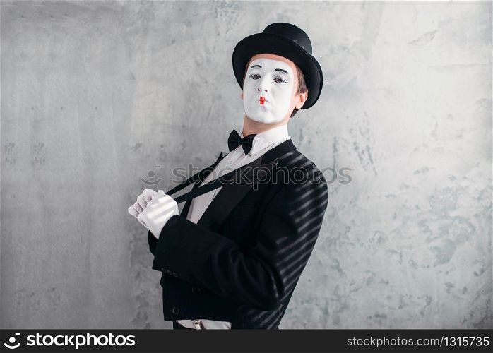 Mime male artist with white makeup mask. Comedy actor in suit, gloves and hat. Mimic person. April fools day concept