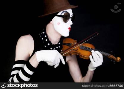 mime playing on small violin in sunglasses on black background