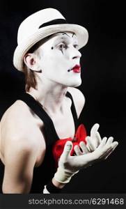 Mime with red bow in a white hat and striped gloves on black background