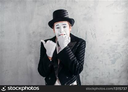 Mimic male person with white makeup mask. Comedy actor in suit, gloves and hat. Pantomime theater artist. April fools day concept