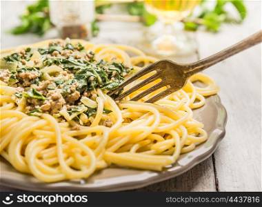 Minced meat and spinach spaghetti in gray plate with fork , close up
