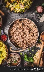 Minced Meat in cooking pot on rustic kitchen table with ingredients , rice and cooked cabbage, top view