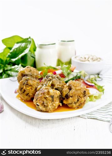 Minced meatballs with spinach, oatmeal and green onions in tomato sauce, vegetable salad in a plate, napkin on a white wooden board background