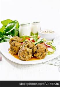 Minced meatballs with spinach, oatmeal and green onions in tomato sauce, vegetable salad in a plate, napkin on a white wooden board background