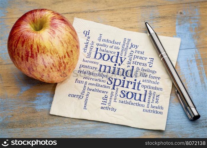 mind, body, spirit and soul concept - word cloud on a napkin with an apple